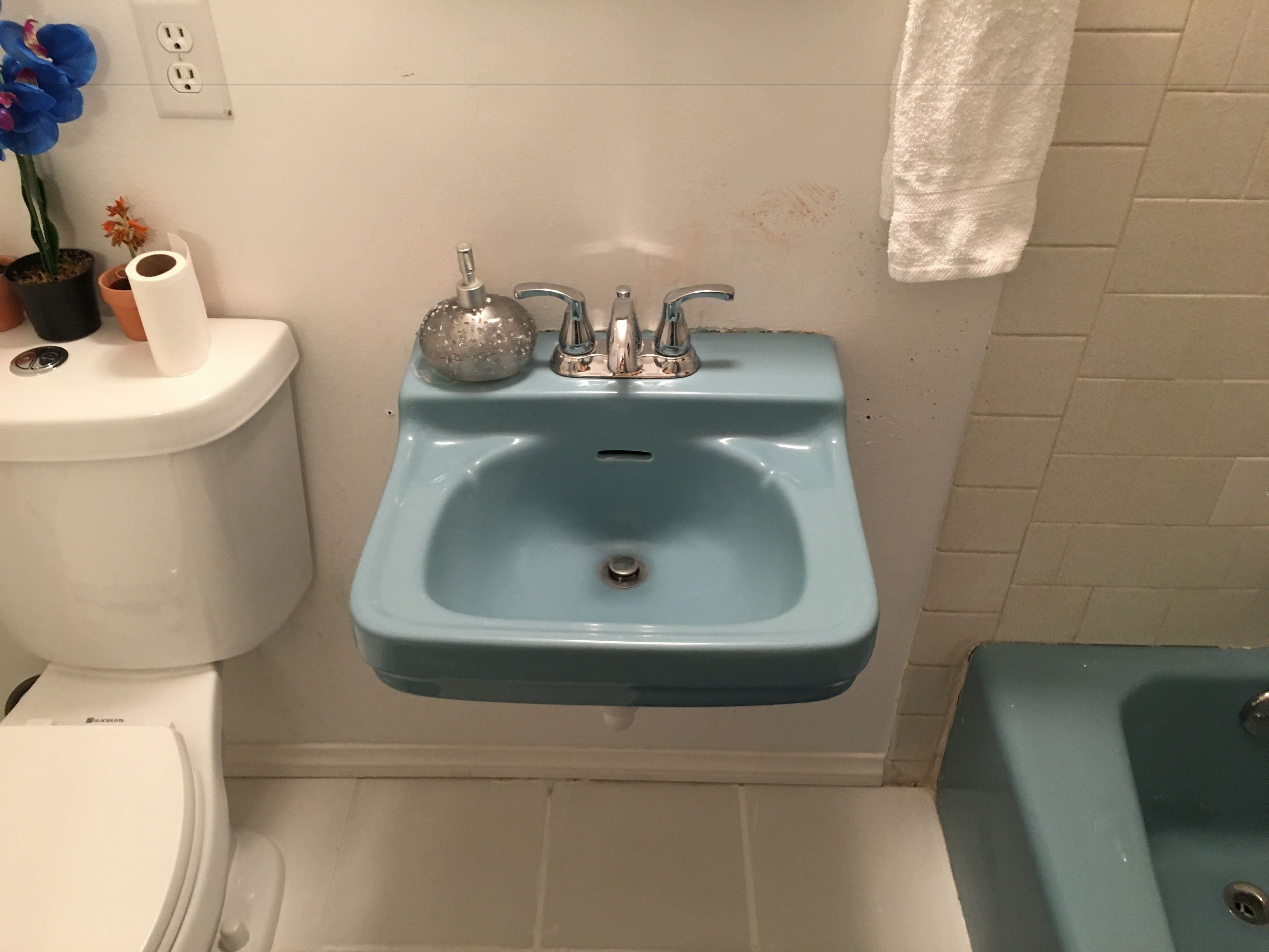 A bathroom with a blue sink, toilet, and bathtub.