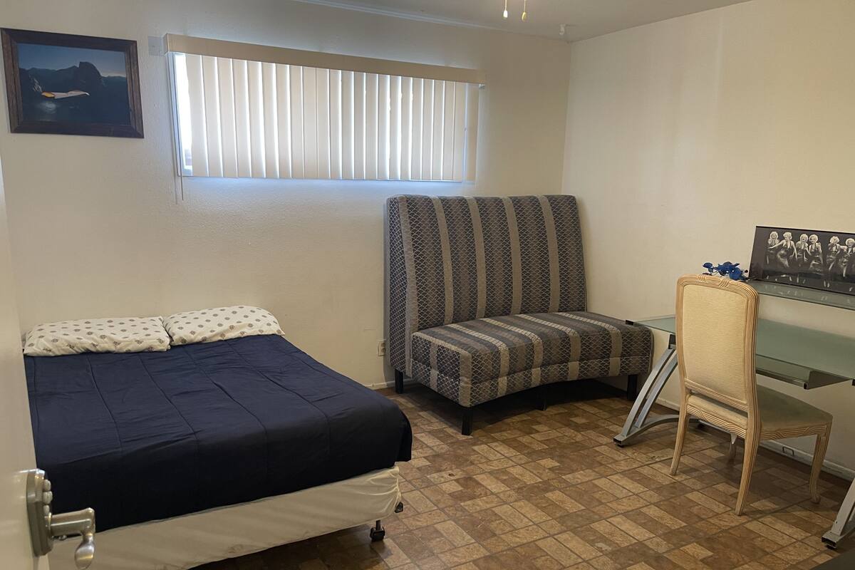 Una habitación pequeña y ordenada con cama, una silla y un escritorio.