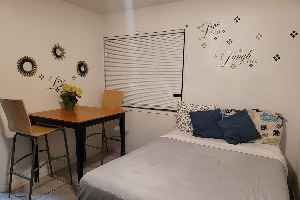 Un dormitorio con cama, escritorio, silla y ventana con persianas.