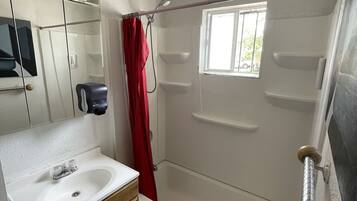 A bathroom with a bathtub, a shower, a sink, and a mirror.
