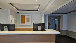 Un mostrador de recepción con un cartel que dice 'RECEPTION', una computadora Dell y una encimera de madera.