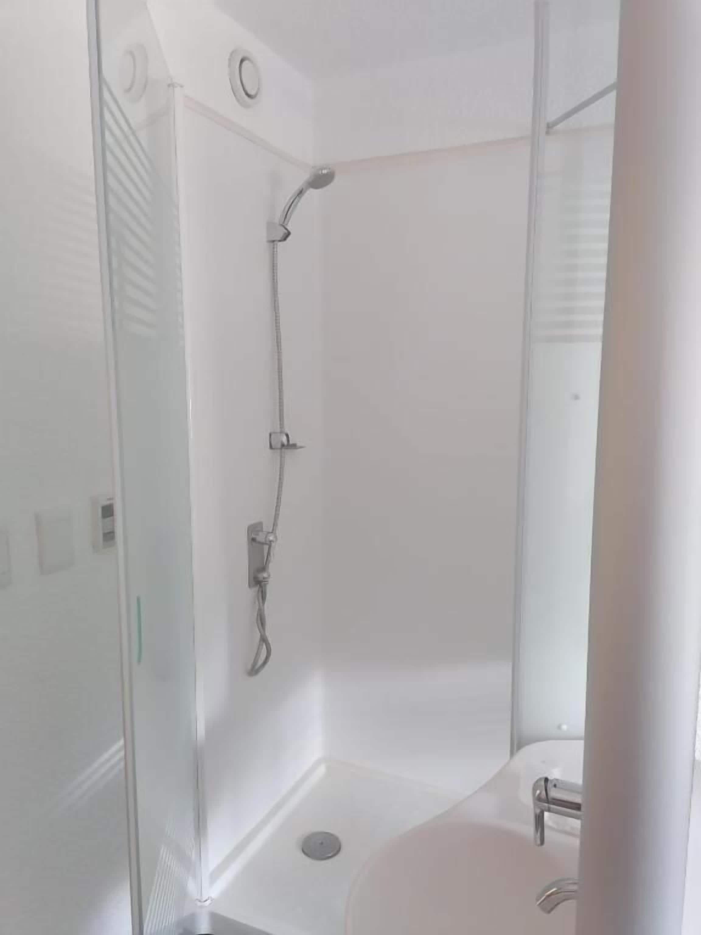 A modern bathroom with a glass shower enclosure, a white sink, and a toilet.