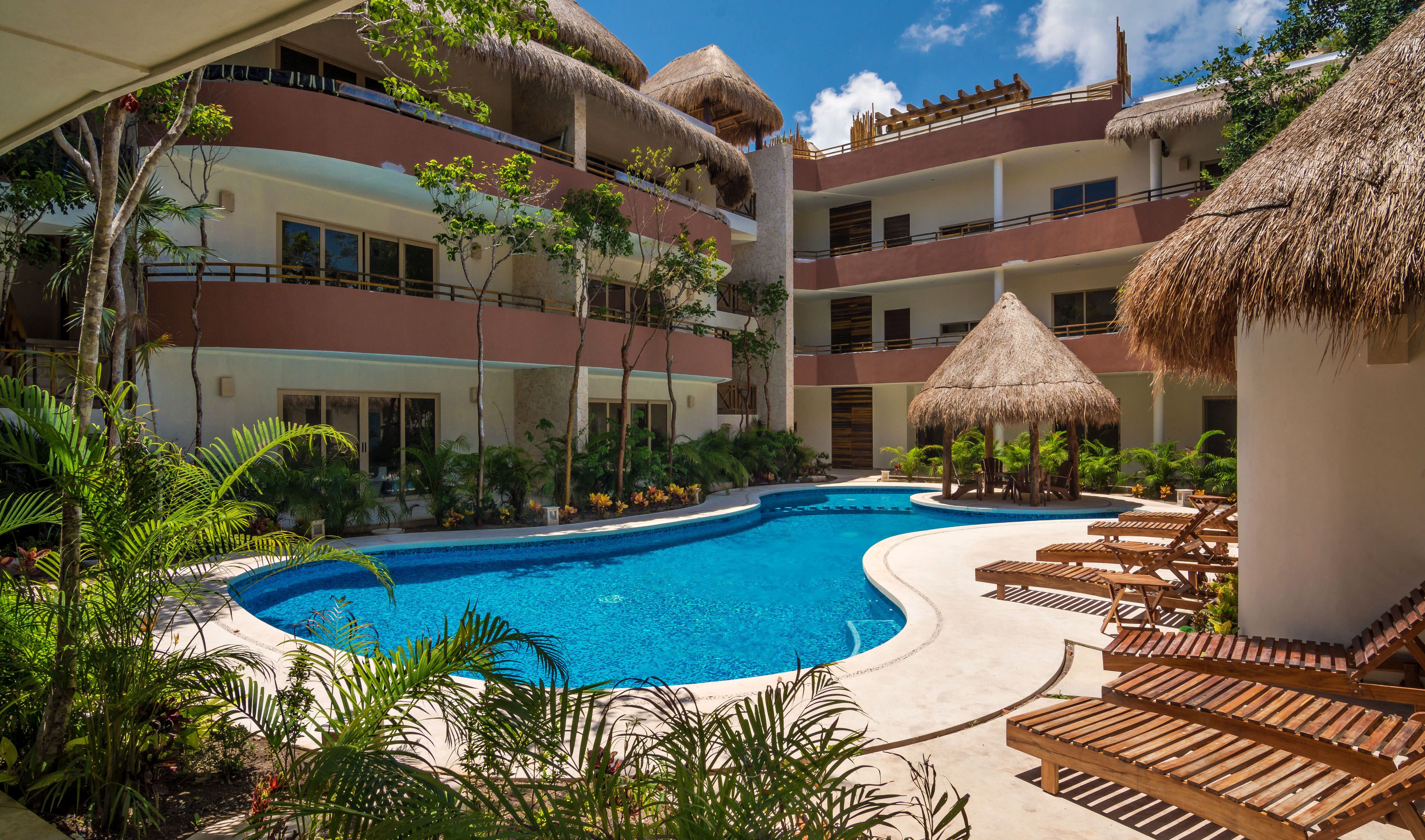 A resort with a central swimming pool, multiple balconies, and thatched-roof structures.
