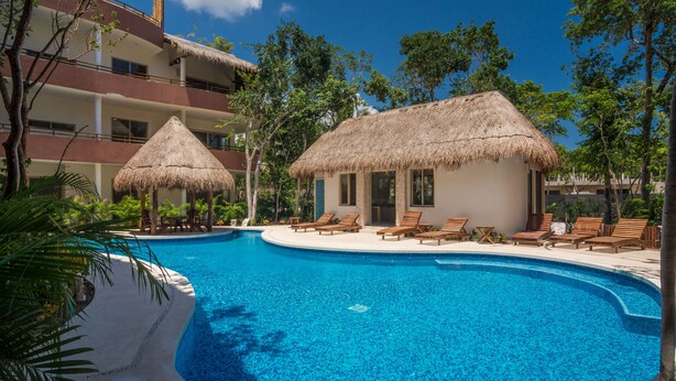 A resort with a swimming pool, thatched-roof huts, and lounge chairs. - Peggy 2 BDRM apt sleeps 4 balcony (Tulum)