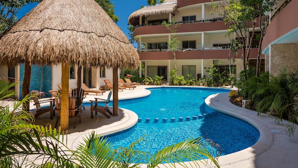 A resort with a swimming pool, a thatched-roof hut, and a multi-story building.
