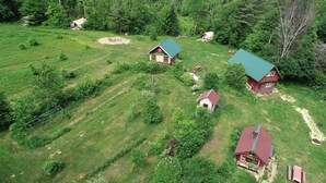 Eine Vogelperspektive auf ein ländliches Anwesen mit mehreren Gebäuden, darunter ein Badehaus, eine Lodge und eine Pizzeria.