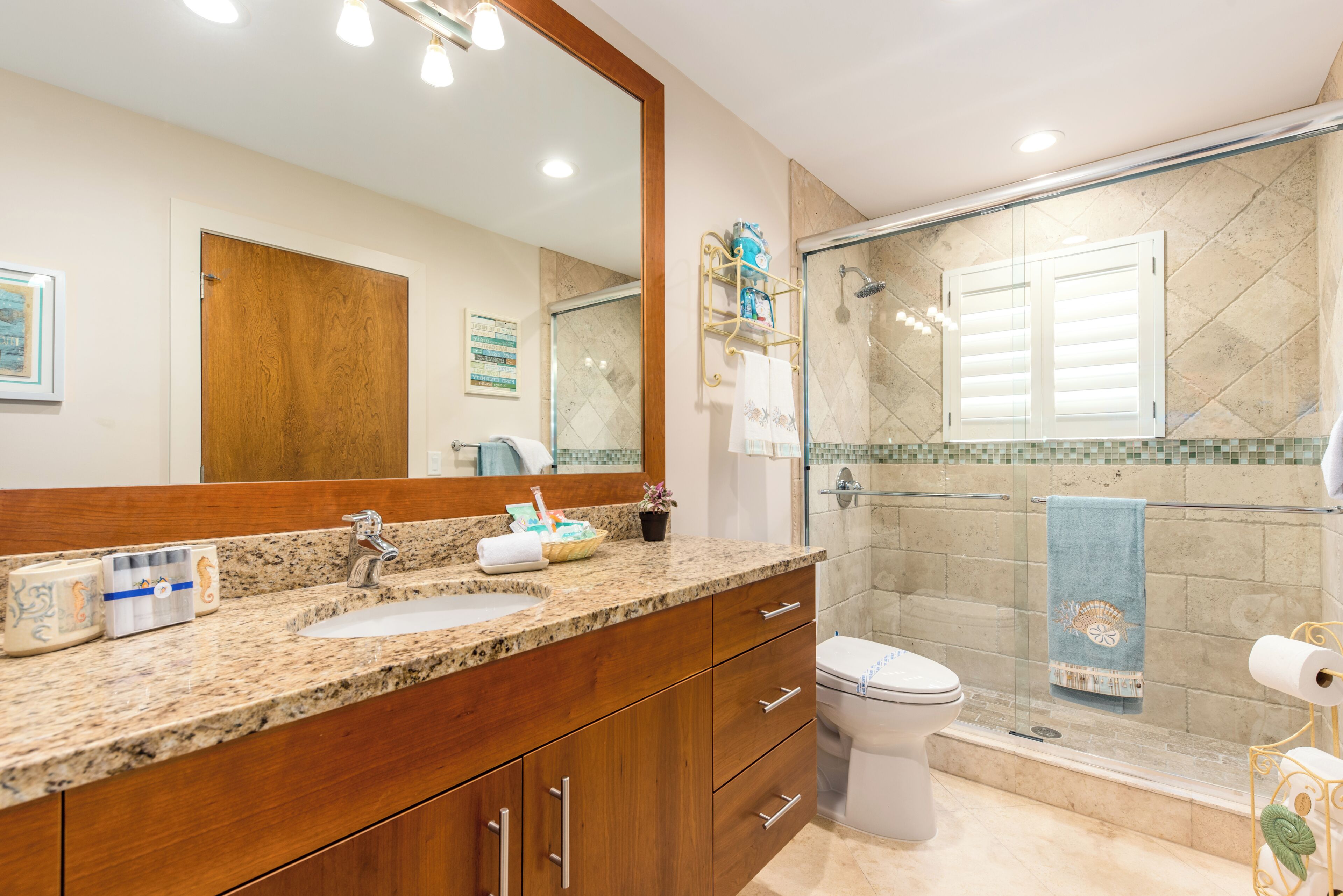 A bathroom with a wooden vanity, a sink, a toilet, and a glass shower enclosure.