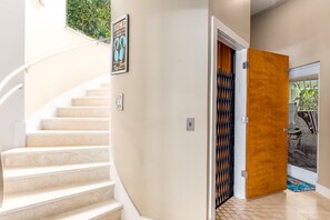 Una escalera conduce a una habitación con una puerta de madera y un cuadro en la pared.