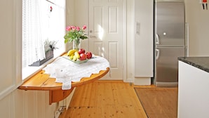 Une cuisine étroite avec un plancher en bois, un réfrigérateur blanc et un four à micro-ondes posé sur le dessus.