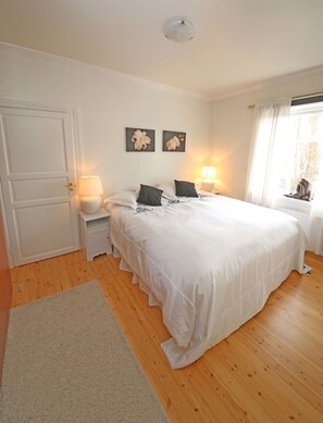 A bedroom with a large bed, two bedside lamps, a door, and two wall-mounted flower paintings. - Best location in 101 Reykjavik (RVK)