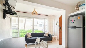 A modern kitchen with a refrigerator, dining table, and chairs. - Beachfront 2BR Apt · Los Corales, Bávaro · Utilities Included (Punta Cana)