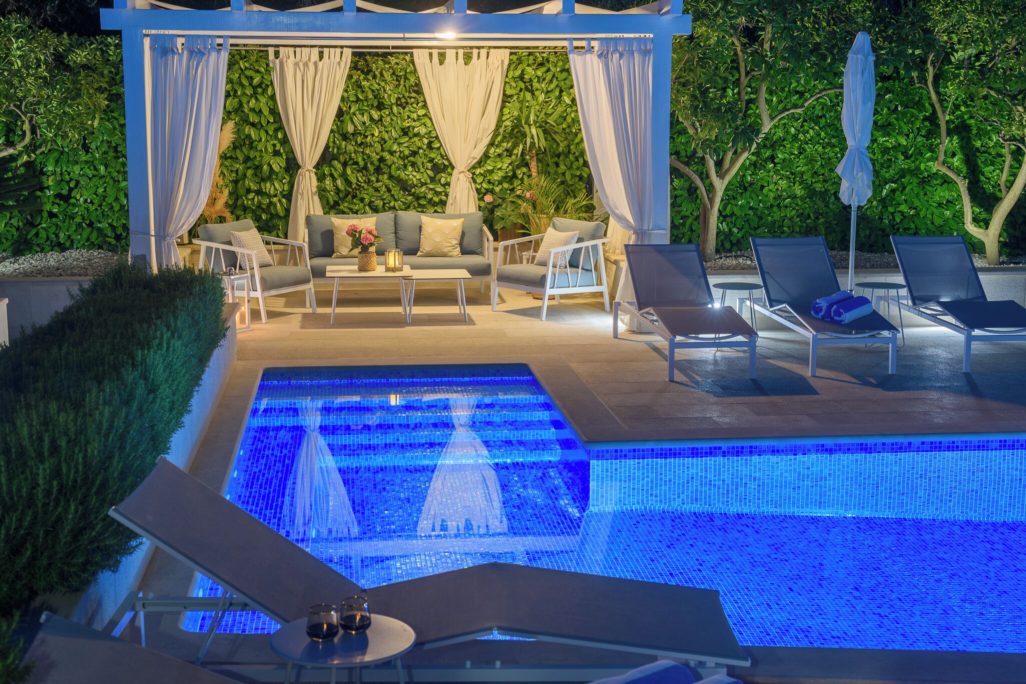 An outdoor pool area with a canopy, lounge chairs, and a seating arrangement.