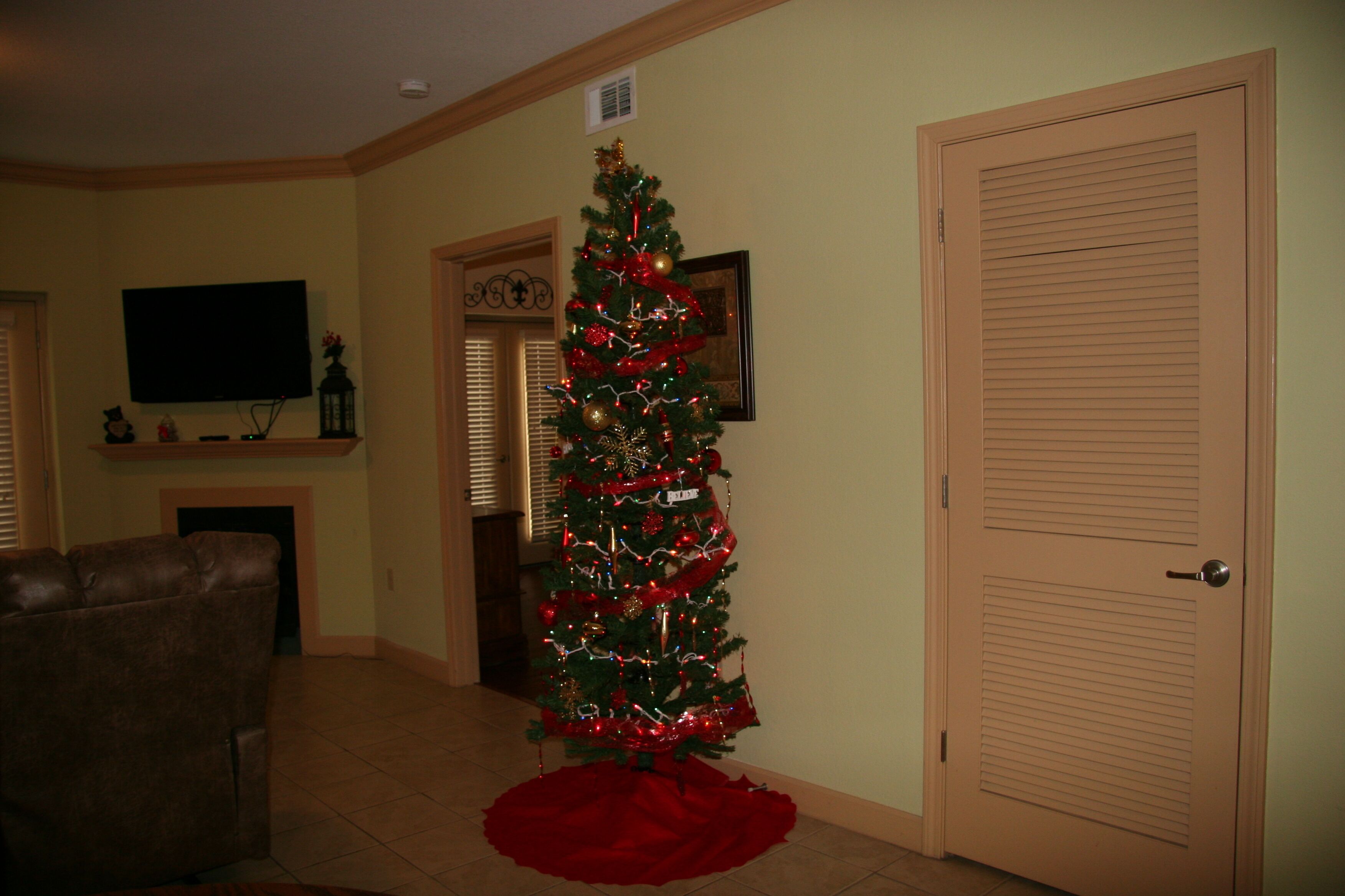 Uma sala de estar com um pinheiro de Natal, uma televisão e uma porta fechada.