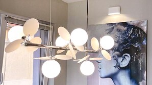 Ein Essbereich mit einem modernen Kronleuchter, einem großen Fenster und einem Gemälde an der Wand.
