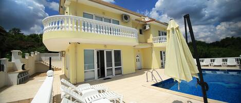 Een buitenzwembad, ligstoelen bij het zwembad