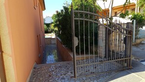 Une entrée fermée par un portail, avec un chemin dallé menant à un bâtiment.