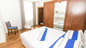 A hotel room with a bed, a chair, a small table, and a wardrobe.