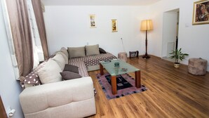 A living room with a sofa, a glass coffee table, a lamp, and a potted plant.