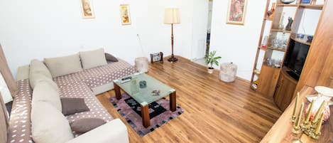 Una sala de estar con sofá, mesa de centro y un mueble de madera con objetos decorativos.