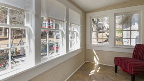 A sunlit room with large windows, a red chair, and a view of the outside. -  Charming One-Story 3BR 3BA Home Just Off The Oxford Square! Deck and Porch! (Oxford)