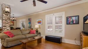 A living room with a stone pillar, wooden flooring, a sofa, a coffee table, and a television on a wooden cabinet. -  Charming One-Story 3BR 3BA Home Just Off The Oxford Square! Deck and Porch! (Oxford)