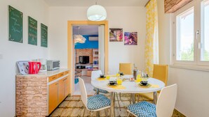 Un coin repas avec une table ronde, des chaises et une cuisine en arrière-plan.