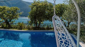 Ein Hängesessel am Pool mit Blick auf das Meer und die Berge.