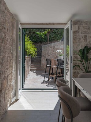 Une terrasse moderne avec un mur en pierre, une table avec des chaises et une plante en pot.