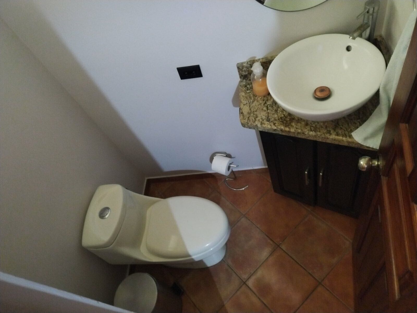 A small bathroom with a toilet, sink, and a towel hanging on the door.