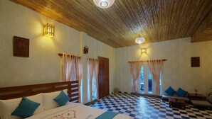 Ein Hotelzimmer mit Schachbrettmuster-Boden, einem Bett mit 'Honey House'-Bettdecke, einer Sofagarnitur und zwei Wandleuchten.
