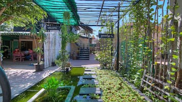 Un jardin avec un bassin, des marches en bois et une clôture en bambou.