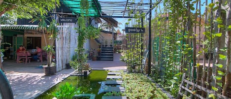 A garden with a pond, wooden steps, and a bamboo fence.