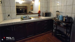 Una cocina equipada con un lavamanos, microondas y diversos electrodomésticos.