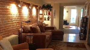 Un salon avec un mur en briques, un canapé, un pouf et un radiateur.