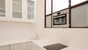 Een keuken met een wit aanrecht, een spoelbak, kastjes en een Bosch oven.