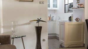 Een moderne keuken met witte kastjes, een ingebouwde oven en een aanrecht met verschillende keukengerei.