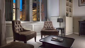 Een kamer met twee bruine fauteuils, een zwarte salontafel, een lamp en een boekenkast.