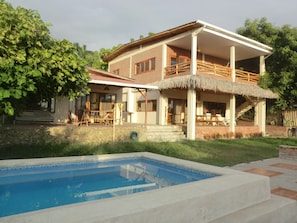 Ein zweistöckiges Haus mit Swimmingpool, einer überdachten Terrasse und einer Treppe, die zum Obergeschoss führt.