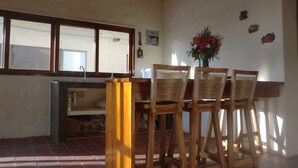 Una cocina con techo de madera, una ventana, un lavabo y una zona de comedor con sillas y una mesa.