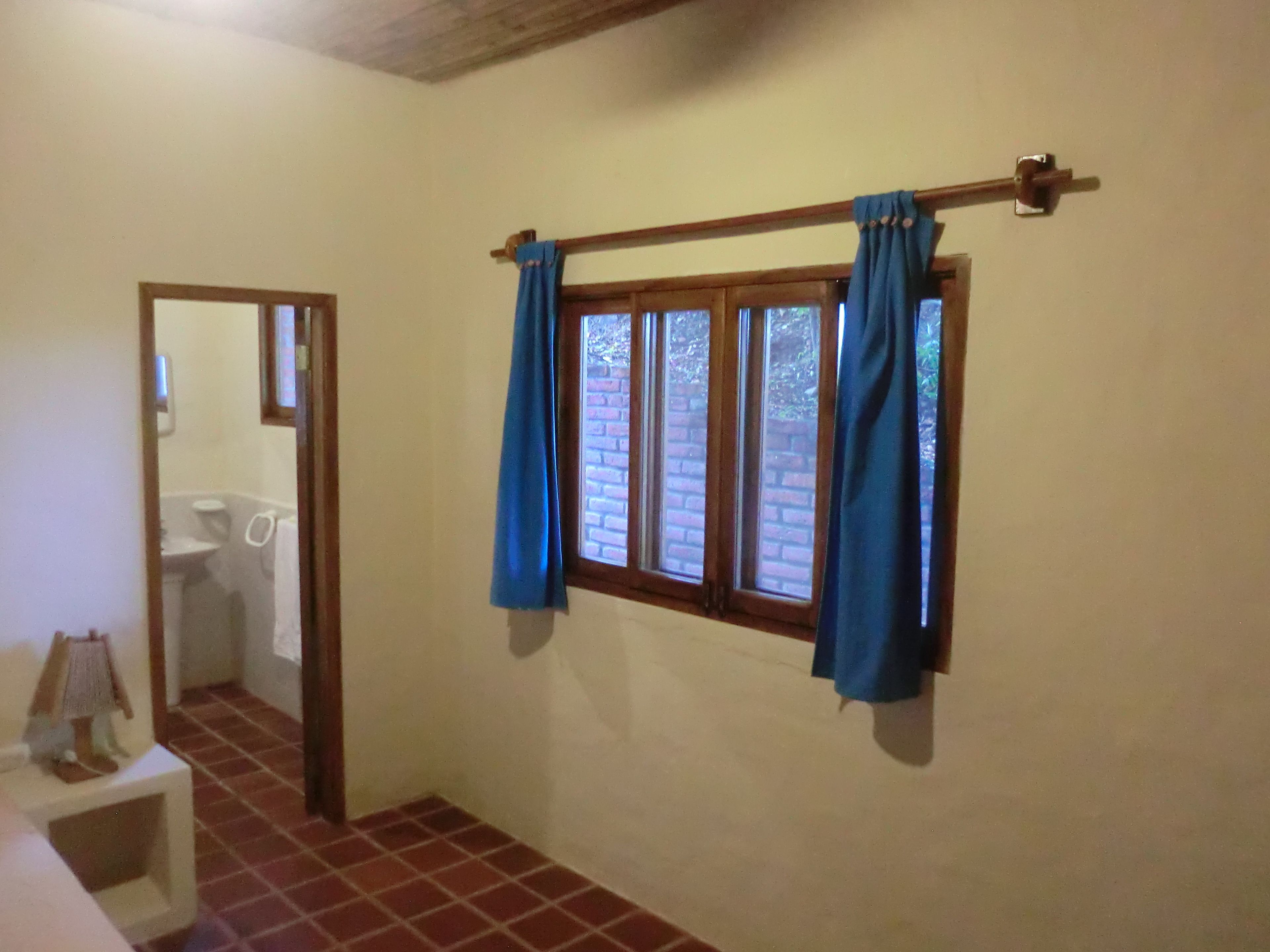 A bathroom with a toilet, a sink, and a window with blue curtains.