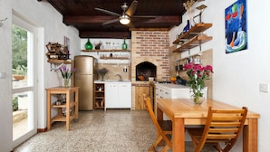 Una cocina con chimenea de ladrillo, armarios de madera y comedor con mesa y sillas.
