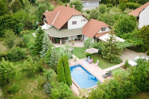 Una zona residencial con piscina, rodeada de exuberante vegetación y casas con techos de tejas rojas.