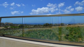 Ein Balkon mit freiem Blick auf eine Küstenlandschaft, darunter Felder und Gebäude in der Ferne.