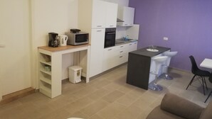 A compact kitchen with white cabinets, a microwave, a coffee maker, and a sink.