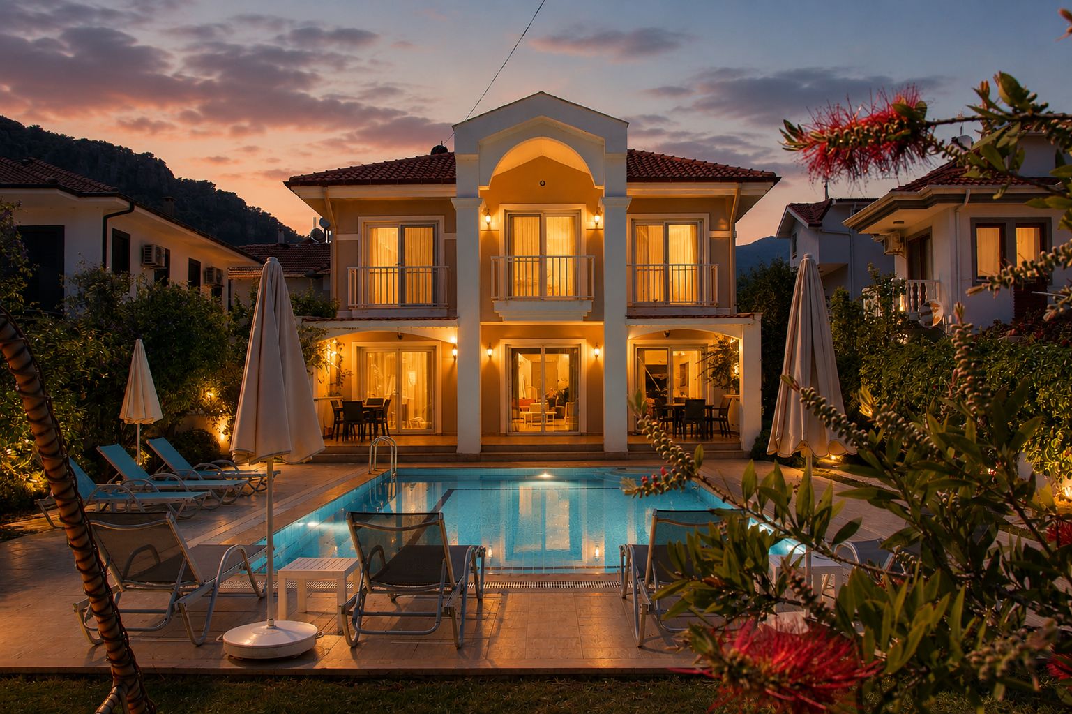 Une maison à deux étages avec une piscine, un espace extérieur aménagé pour s’asseoir et une entrée bien éclairée.