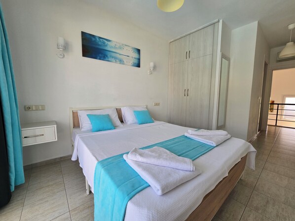 A neatly arranged bedroom with a bed, bedside tables, a wardrobe, and a painting on the wall.