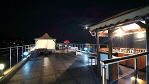 A rooftop terrace with a bar area, outdoor seating, and a covered section.
