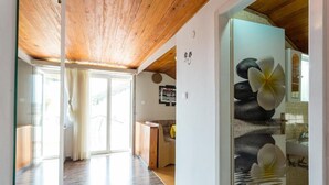 Ein geräumiger Flur mit Holzbalkendecke, einer Glastür zum Balkon und einer Küchenzeile mit dekorativer Wand.