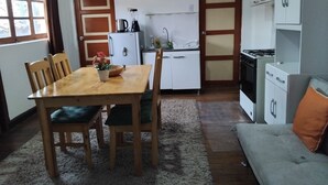 A compact kitchen with a dining table, chairs, a refrigerator, a stove, and a sink. - Studio for rent in Cusco city center! (Cusco)