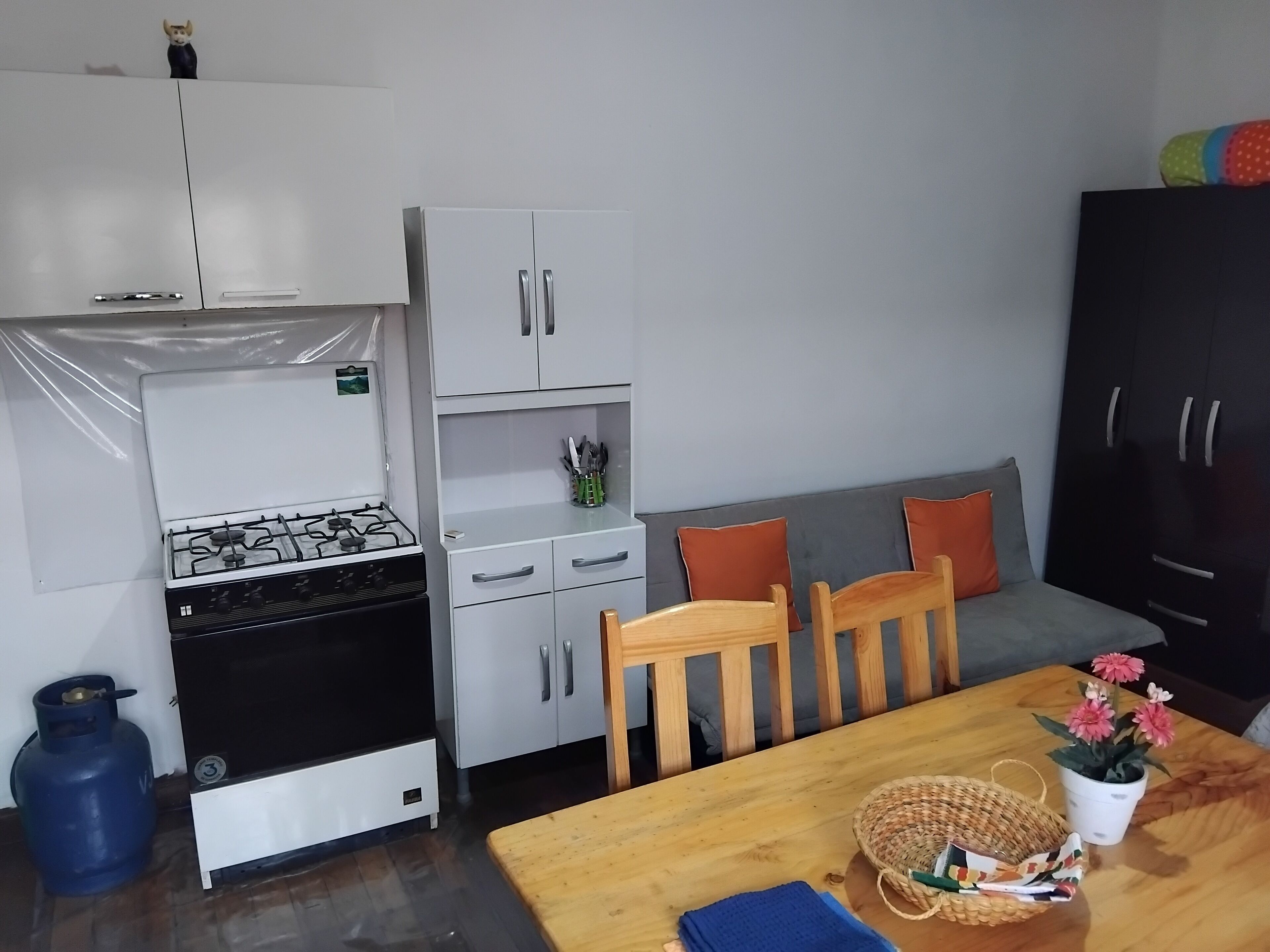 A compact kitchen with a gas stove, a refrigerator, and a dining area with a table and chairs.